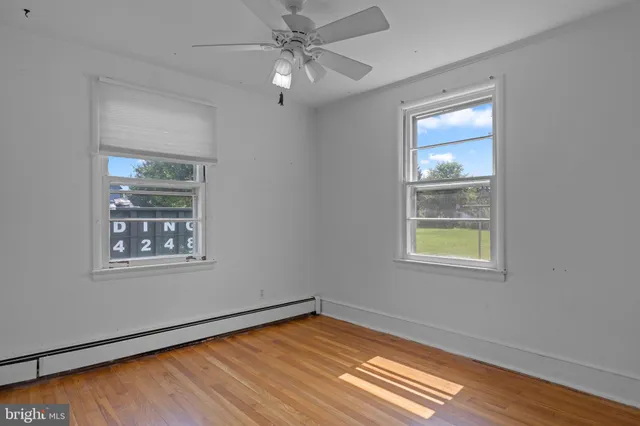 an empty room with wooden floor chandelier fan and windows