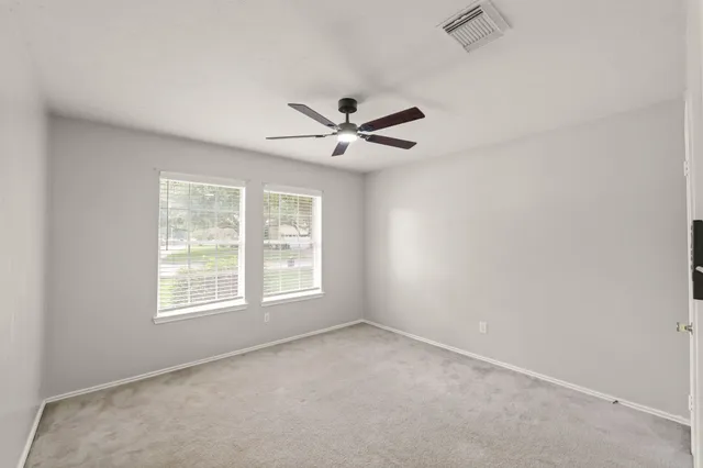 an empty room with windows and ceiling fan