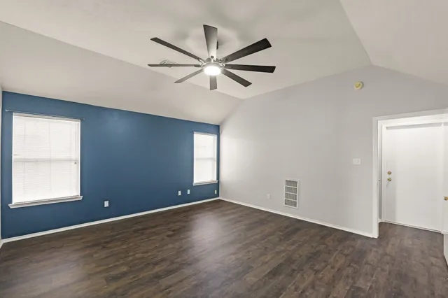 a view of a big room with wooden floor and windows