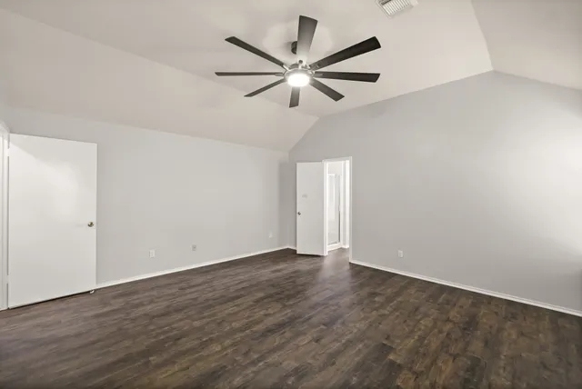 an empty room with wooden floor and ceiling fan