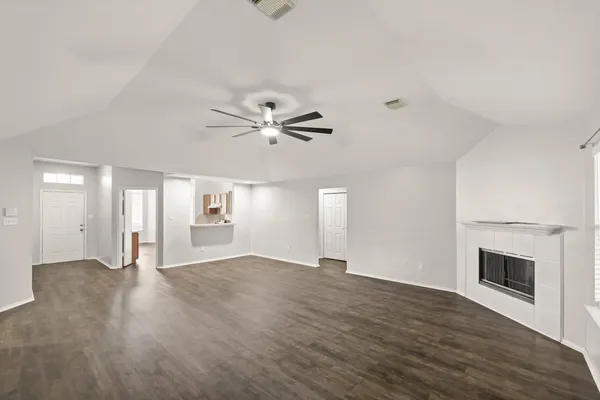 an empty room with wooden floor fan and windows