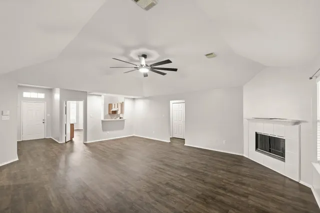 an empty room with wooden floor fan and windows