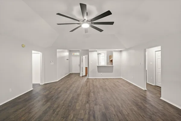 a view of empty room with wooden floor and ceiling fan
