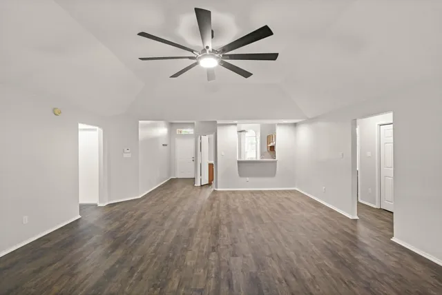 a view of empty room with wooden floor and ceiling fan