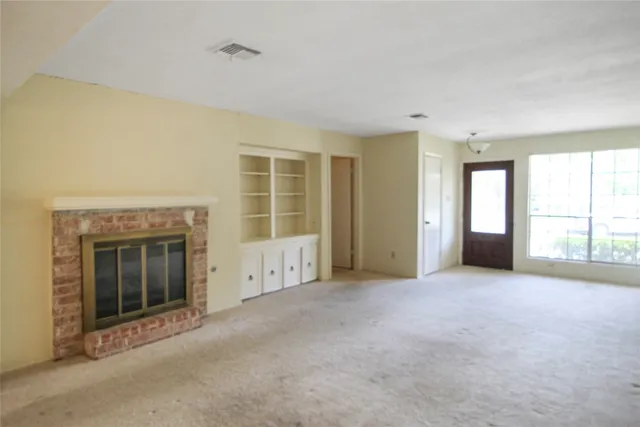 an empty room with windows and fireplace