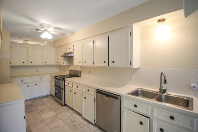 a kitchen with a sink dishwasher and white cabinets with wooden floor