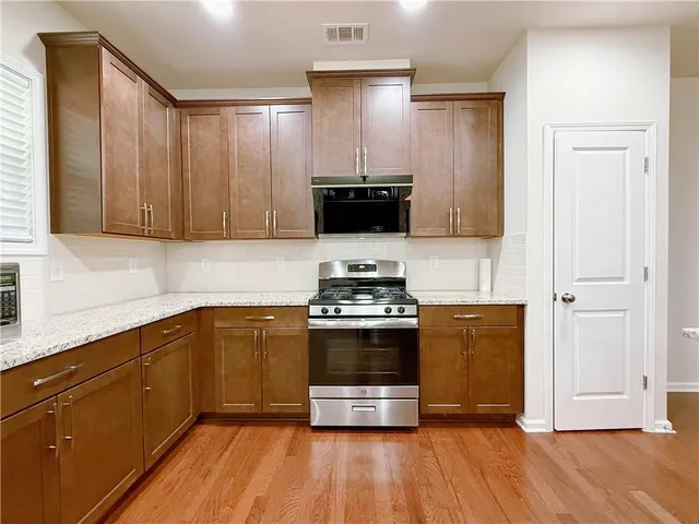 a kitchen with granite countertop a stove and a wooden cabinets