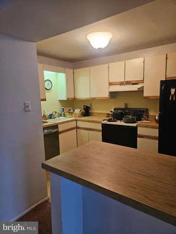 a kitchen with stainless steel appliances a sink a stove a refrigerator cabinets and a window