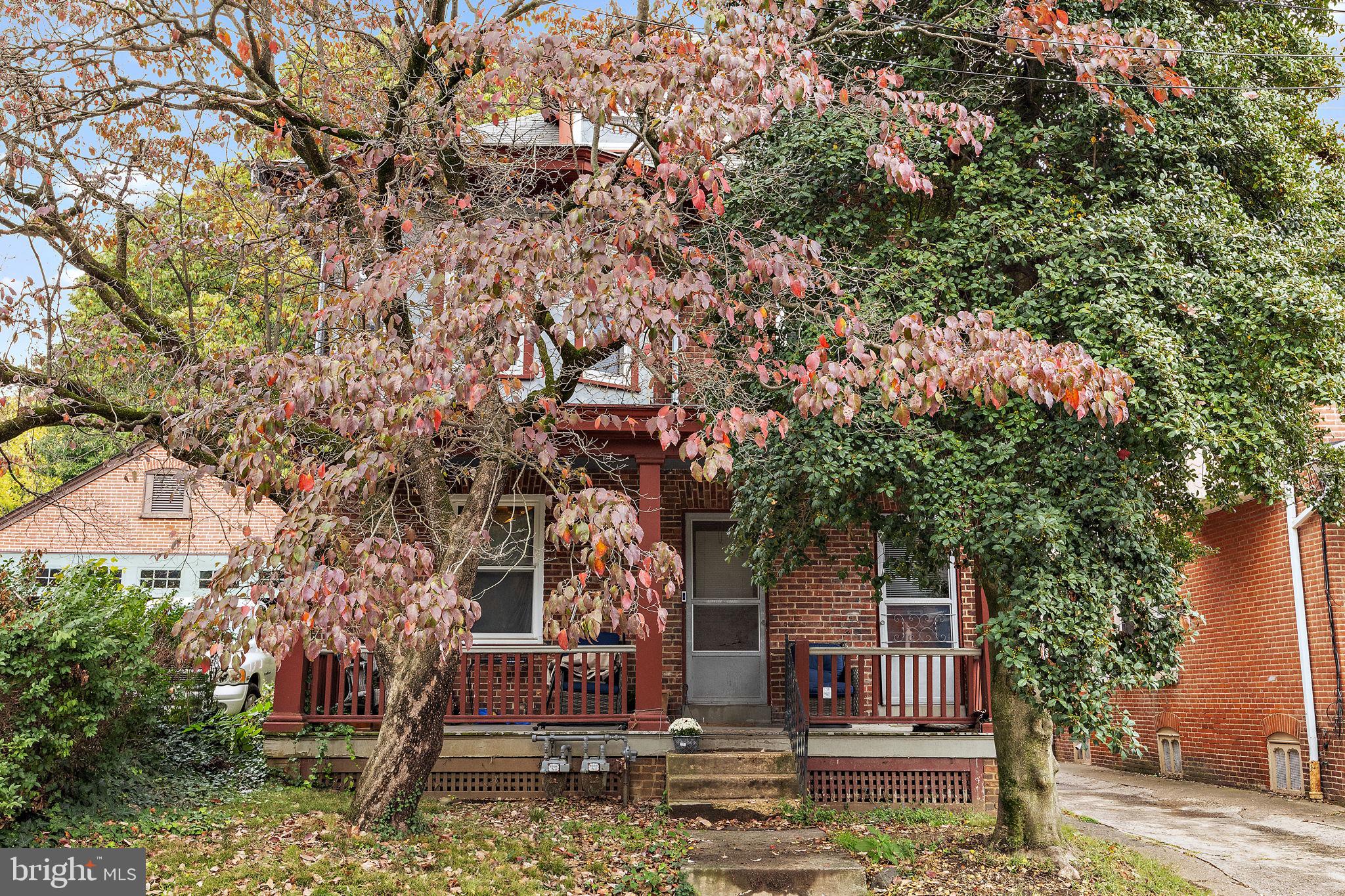 a front view of house with sign board and trees