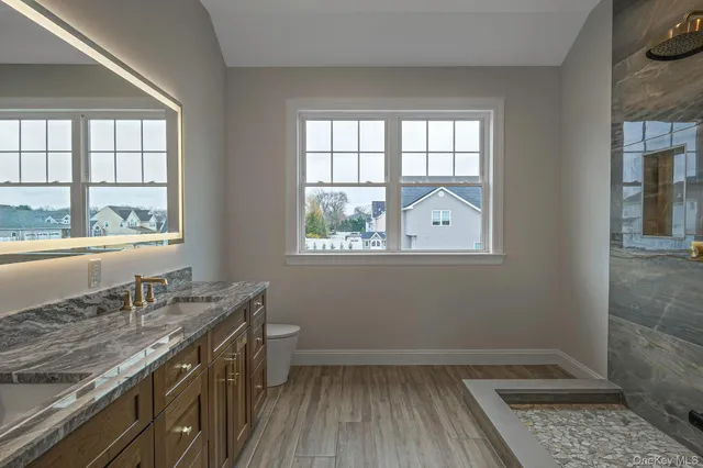 a bathroom with a granite countertop sink toilet and window