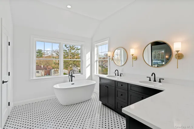 a bathroom with a double vanity sink a mirror and a bathtub