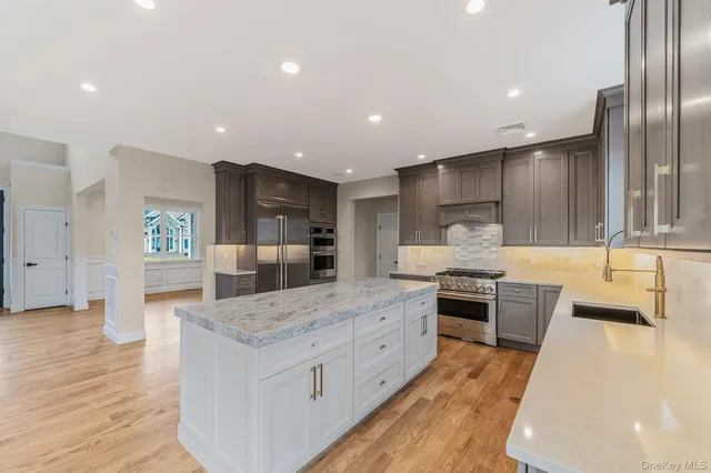 a large kitchen with stainless steel appliances kitchen island granite countertop a large counter top and wooden floors