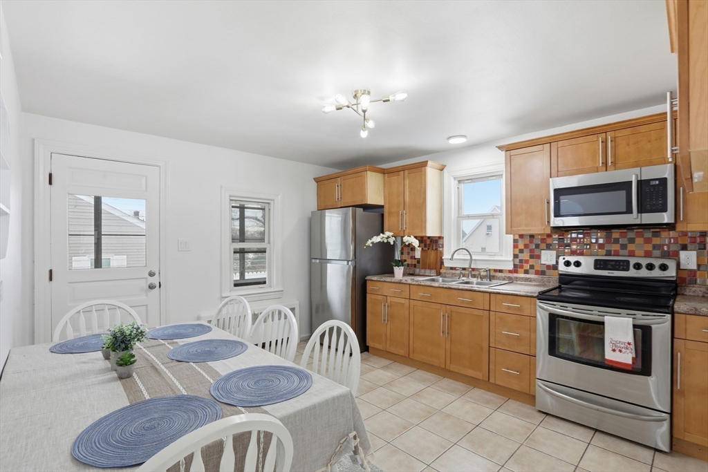 39 Phebe Avenue Lowell, MA 01854 - Photo 6 of 20 a kitchen with stainless steel appliances granite countertop a stove top oven a sink dishwasher a dining table and chairs with wooden floor
