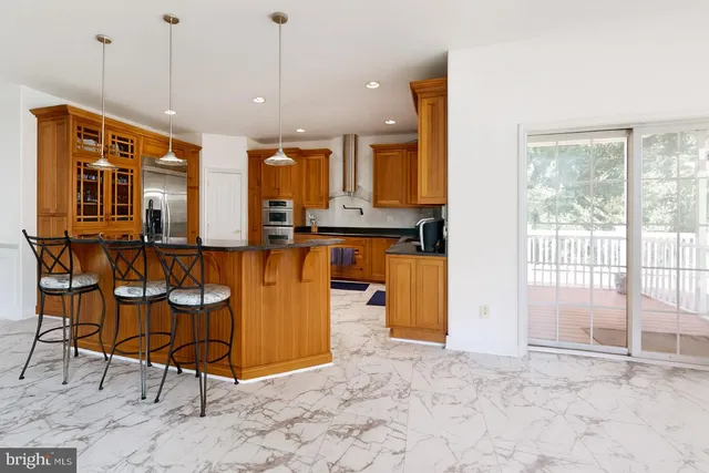 a view of an empty room with wooden floor and a kitchen