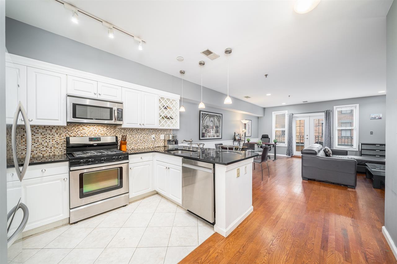 901 Madison Street, Unit 5F Hoboken, NJ 07030 - Photo 1 of 1 a kitchen with stainless steel appliances granite countertop a stove top oven a sink dishwasher a dining table and chairs with wooden floor