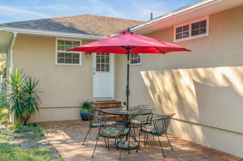 347 Lobelia Road St. Augustine, FL 32086 - Photo 23 of 40 a patio with a table and chairs under an umbrella