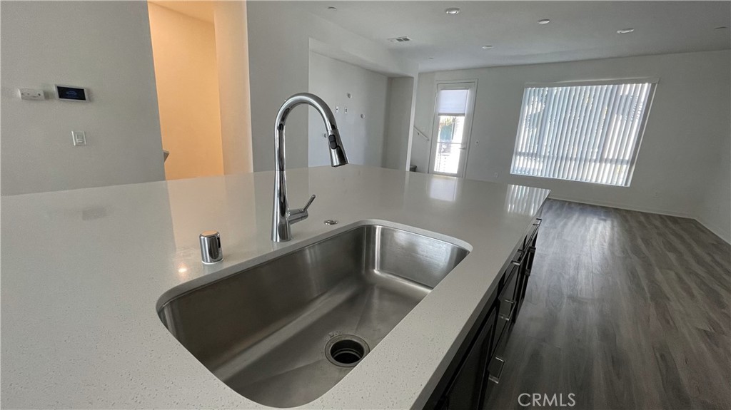 115 Citysquare Irvine, CA 92614 - Photo 11 of 30 a kitchen with kitchen island a sink wooden floor and a large window