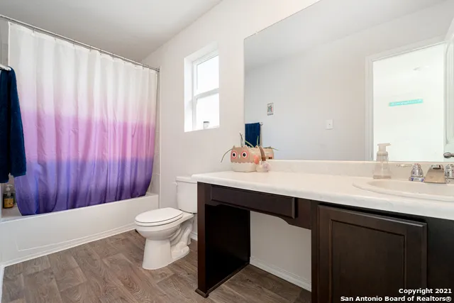 a bathroom with a sink a toilet a large mirror and shower curtain