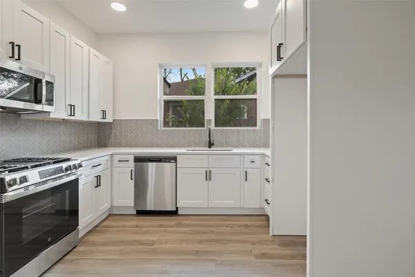 a kitchen with granite countertop a stove a sink and a microwave