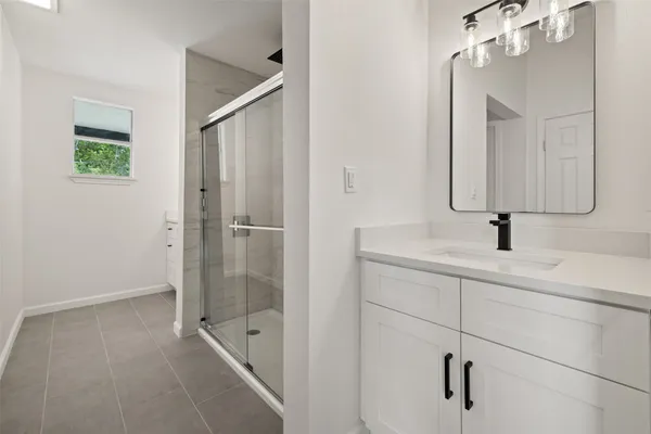 a bathroom with a shower sink and mirror