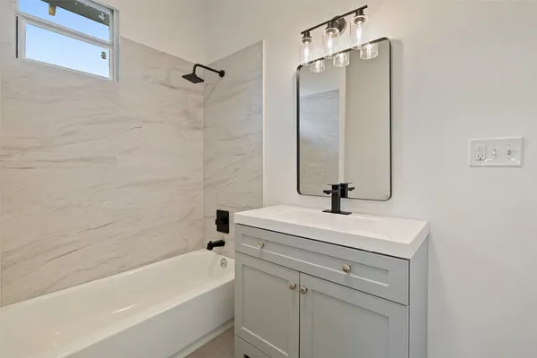 a bathroom with a sink a vanity a mirror and a bathtub