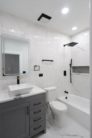 a bathroom with a toilet a sink a mirror a bathtub and vanity