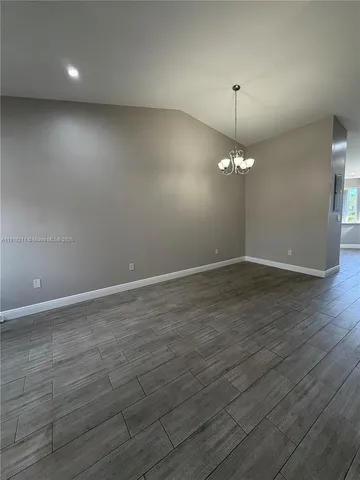 an empty room with wooden floor and chandelier