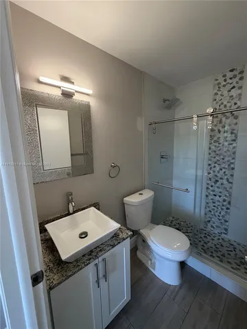 a bathroom with a granite countertop toilet sink and mirror