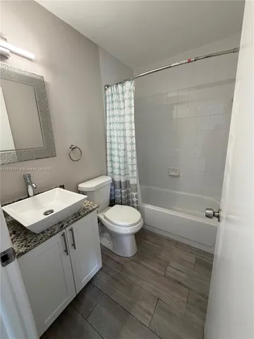 a bathroom with a granite countertop sink toilet a mirror and shower
