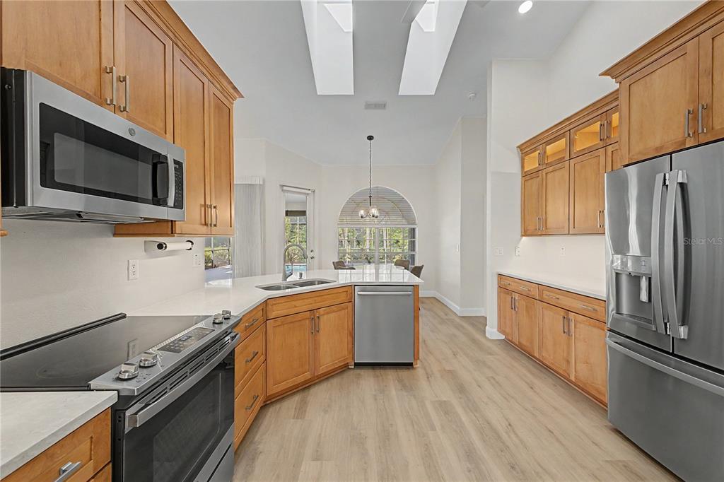 15031 Surrey Bend Spring Hill, FL 34609 - Photo 21 of 77 a large kitchen with stainless steel appliances granite countertop a stove a sink and a microwave