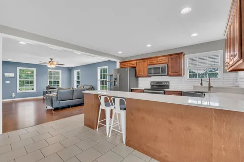 a large living room with stainless steel appliances granite countertop a couch and a large window