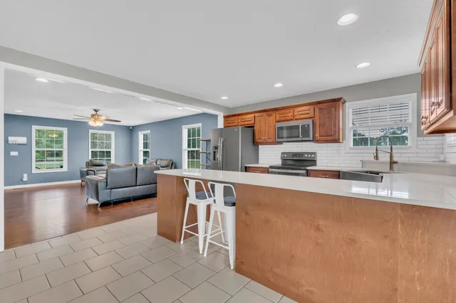 a large living room with stainless steel appliances granite countertop a couch and a large window