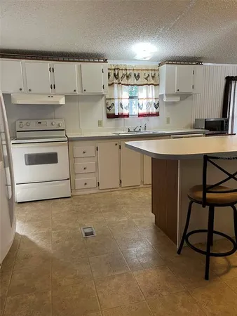 a kitchen with granite countertop a stove a sink and white cabinets
