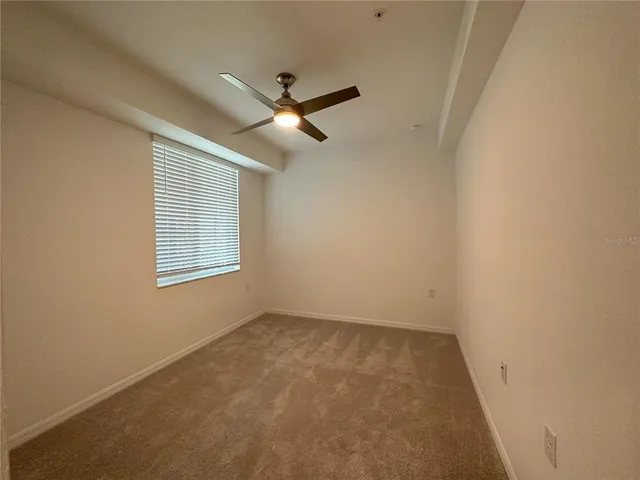 en empty room with windows and a ceiling fan
