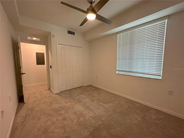 an empty room with chandelier fan and windows