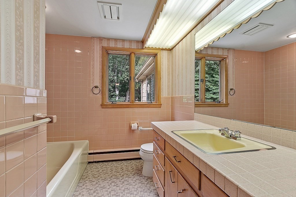 911 Main Street Reading, MA 01867 - Photo 18 of 42 a bathroom with a granite countertop sink a large mirror a bathtub and next to a window