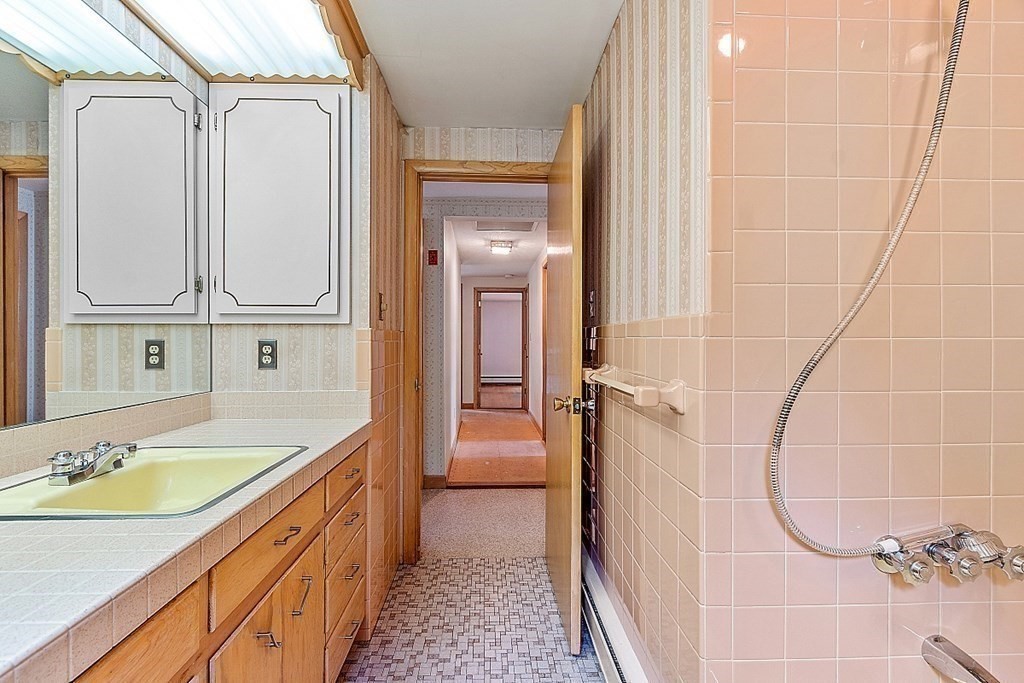 911 Main Street Reading, MA 01867 - Photo 19 of 42 a bathroom with a granite countertop sink a mirror and a bathtub