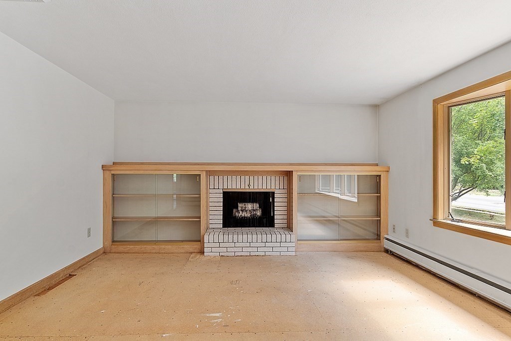 911 Main Street Reading, MA 01867 - Photo 9 of 42 an empty room with a fireplace and window