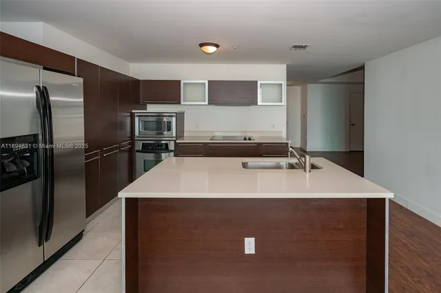 a large kitchen with a sink stainless steel appliances and cabinets