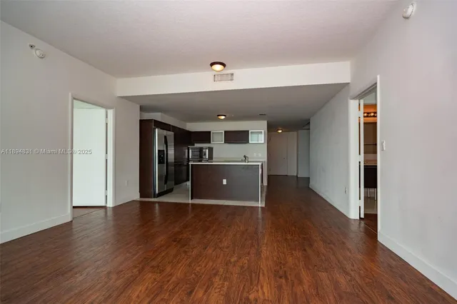 a view of a kitchen with a fridge and wooden floor