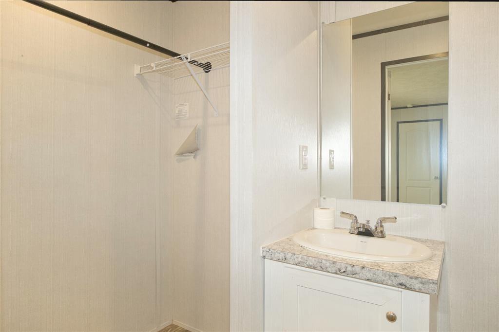 60 Tecumseh Road Valley View, TX 76272 - Photo 14 of 20 Built-in vanity with an oval sink, speckled countertop, and wall-mounted mirror