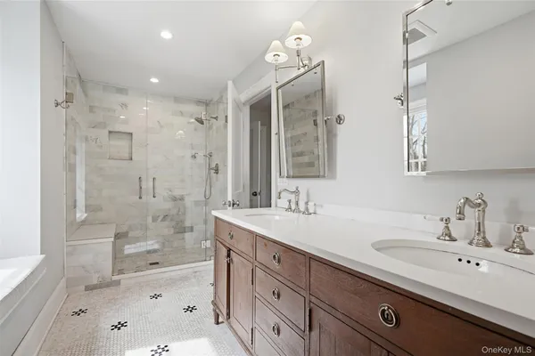 a bathroom with a sink double vanity granite tub shower and a mirror