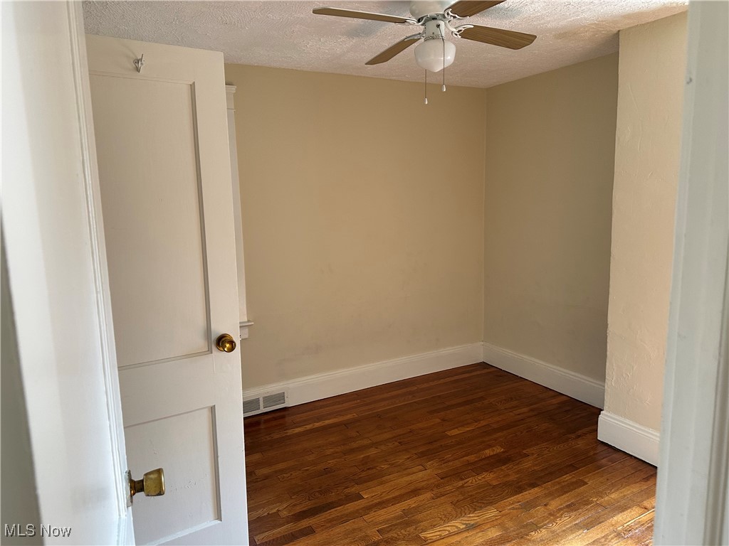 1596 Wood Road Cleveland Heights, OH 44121 - Photo 12 of 25 Unfurnished room featuring a textured ceiling, wood finished floors, and a ceiling fan