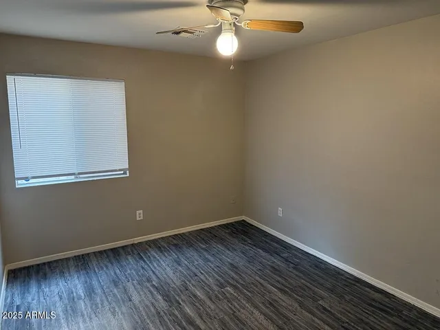 an empty room with wooden floor closet and fan