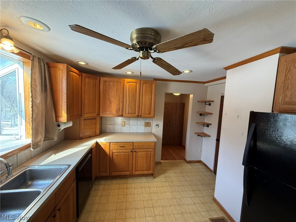 6784 Old Zoarville Road Northeast Dover, OH 44622 - Photo 14 of 50 Kitchen with black appliances, ornamental molding, light countertops, wood finish cabinetry, and light floors