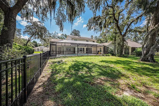 a view of a house with a small yard and large trees