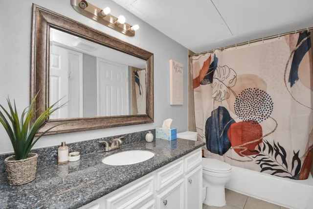 a bathroom with a granite countertop sink a toilet a mirror and bathtub