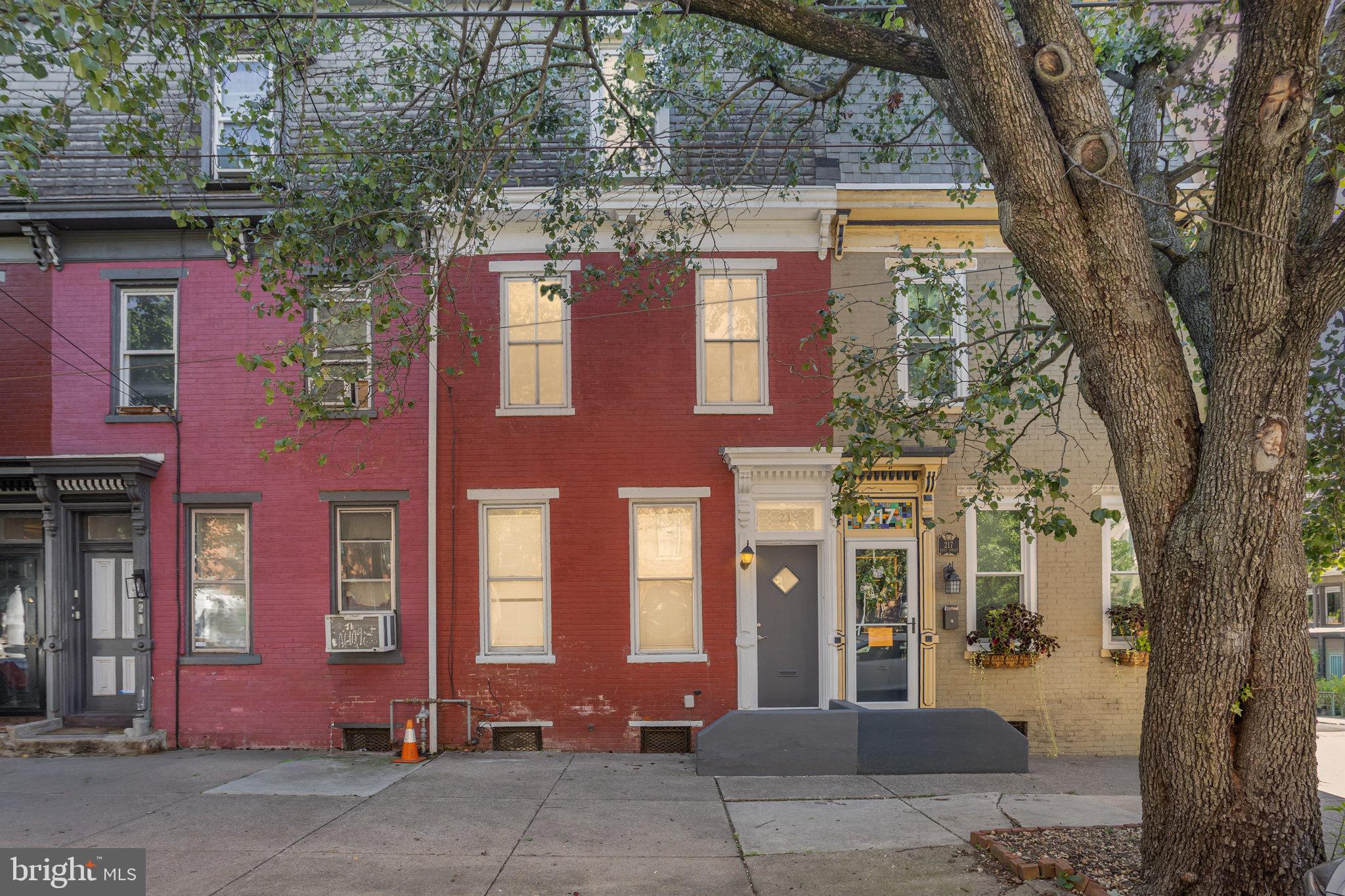 front view of a brick house with a large tree