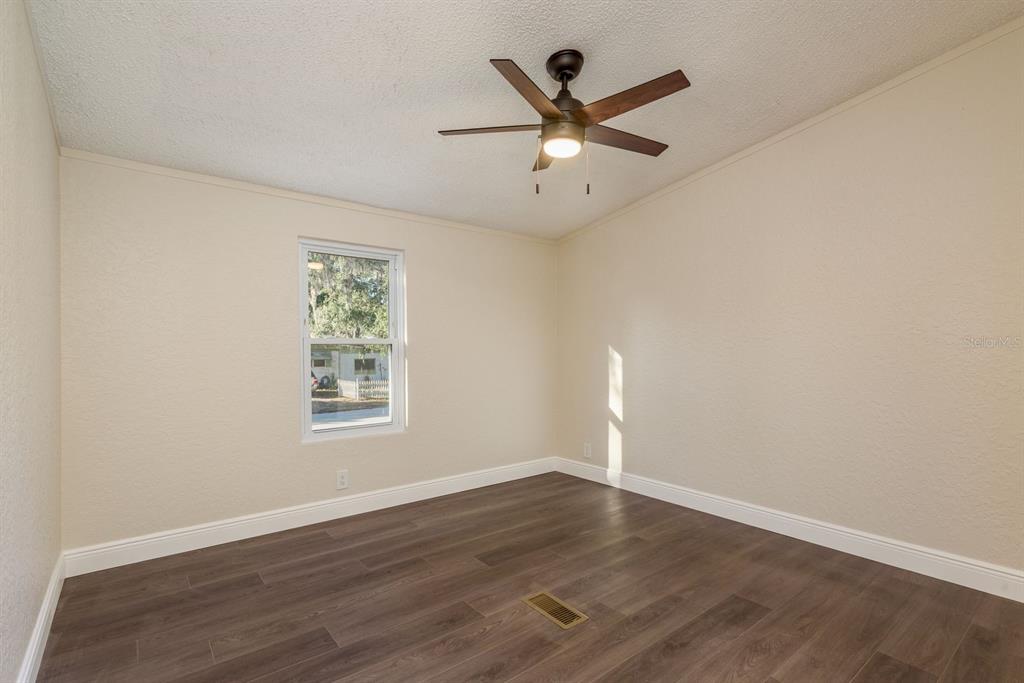 6707 Celeste Lane New Port Richey, FL 34653 - Photo 11 of 21 an empty room with wooden floor ceiling fan and windows