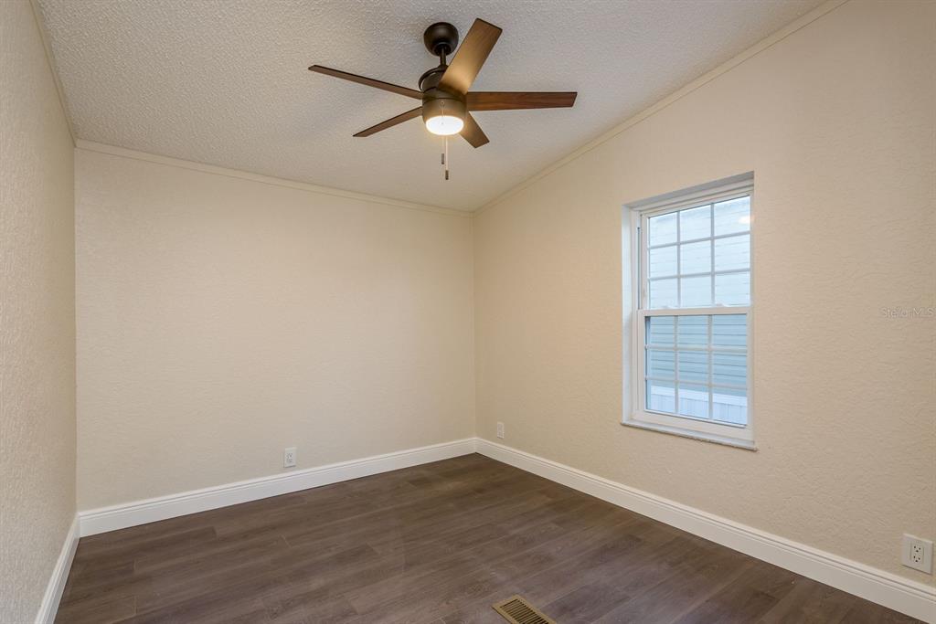 6707 Celeste Lane New Port Richey, FL 34653 - Photo 14 of 21 an empty room with wooden floor fan and windows